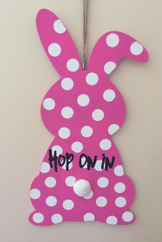 This adorable wooden hand painted pink bunny with white polka dots would look great on your front door. "Hop on in" is painted across the middle of the bunny to welcome family and friends.: 